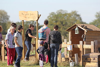 Un groupe de personnes découvrent une activité pour enfants lors d'une sortie à la ferme